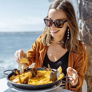 Smiling woman enjoying meal at restaurant on the water