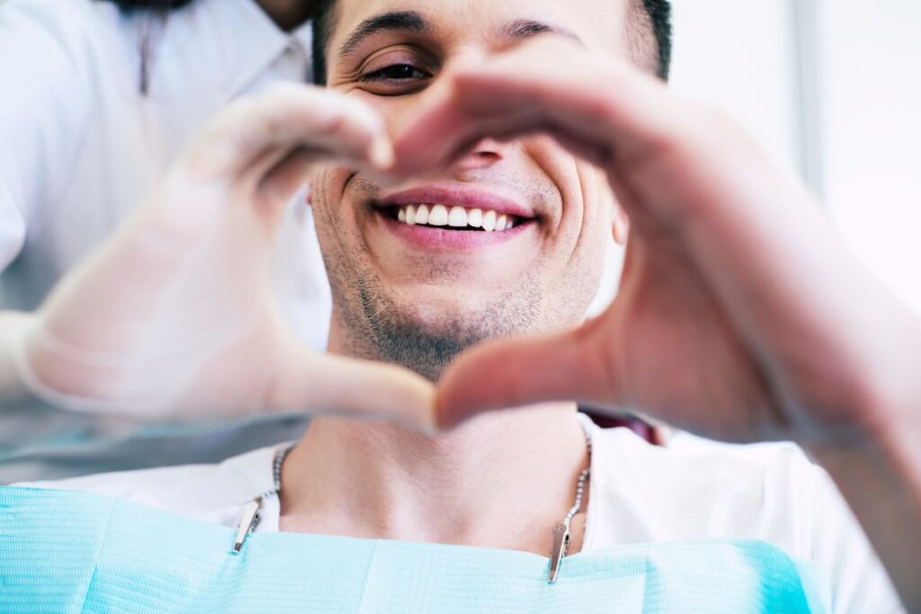 A man making a heart with his hands at the dentist.