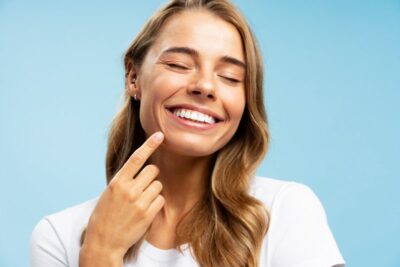 Woman smiling and pointing to her teeth.