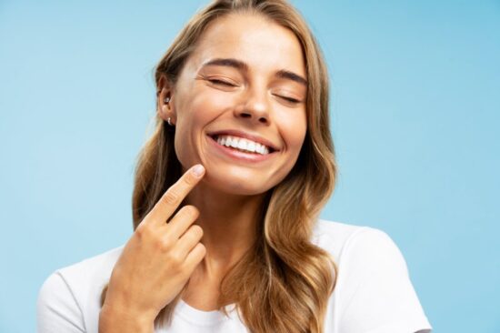 Woman smiling and pointing to her teeth.
